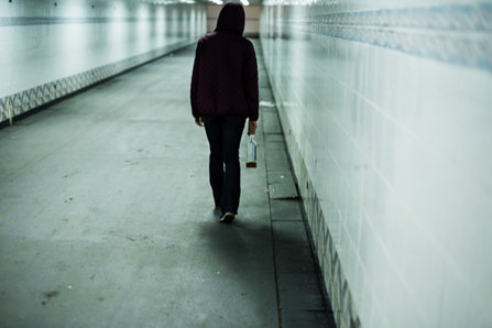 An alcoholic woman is walking in a tunnel.